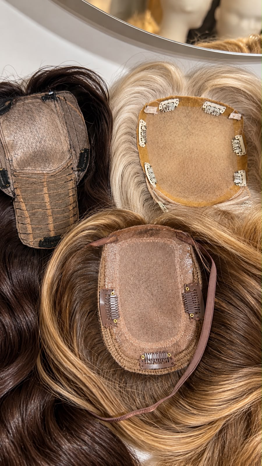 Varios toppers de pelo natural con sus bases, en distintos tonos